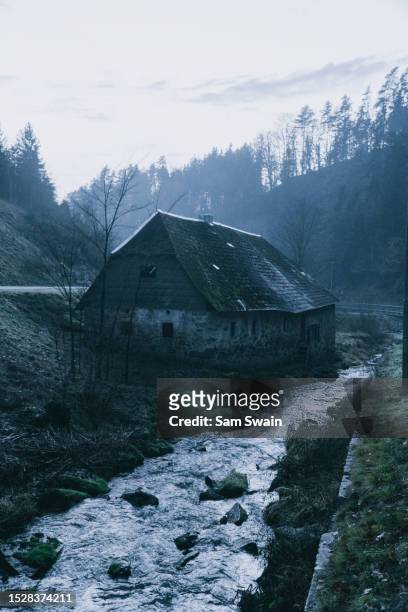 old house under a bridge next to a stream during winter in upper austria. - gmunden austria stock pictures, royalty-free photos & images