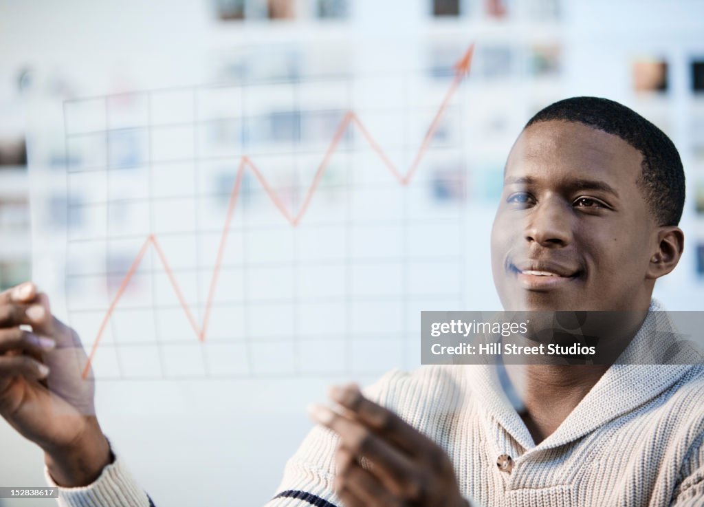 Black businessman looking at line graph