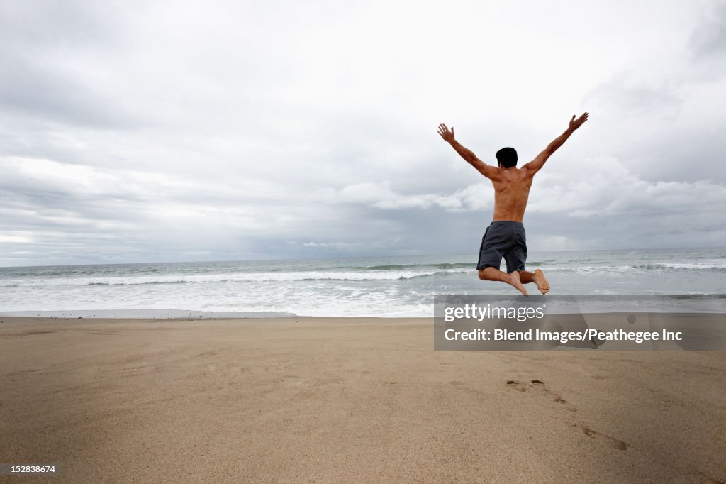 Young man jumping for joy on beach