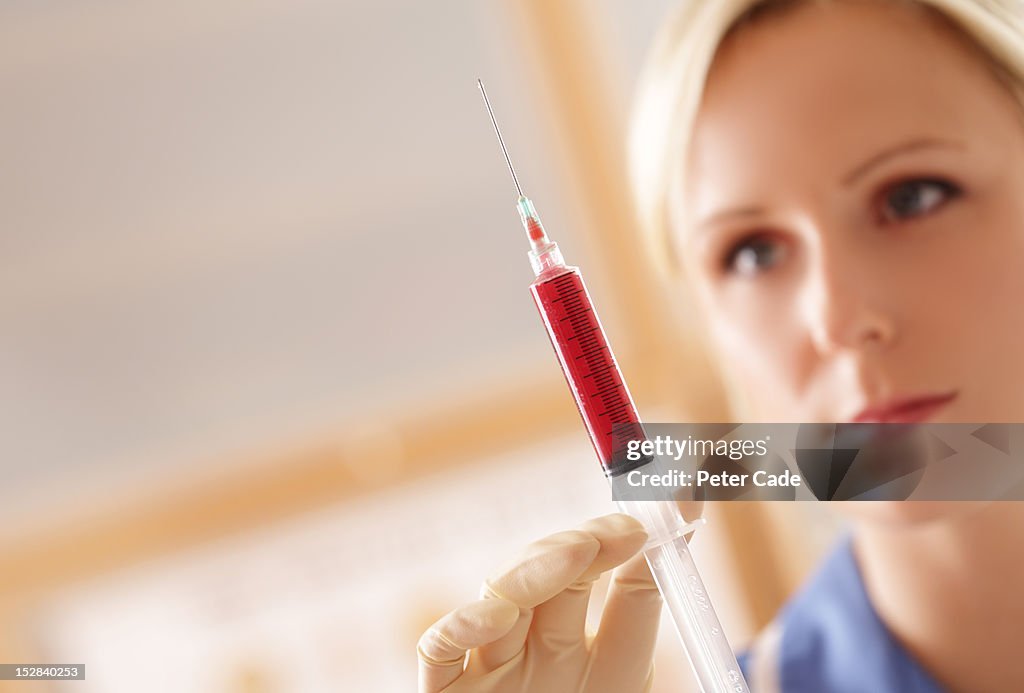 Nurse holding syringe containing red liquid