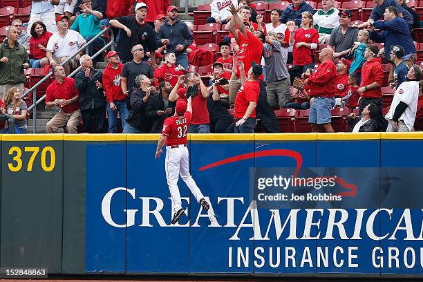 Jay Bruce of the Cincinnati Reds climbs the outfield wall but is not able to catch a home run hit by Carlos Gomez of the Milwaukee Brewers in the...
