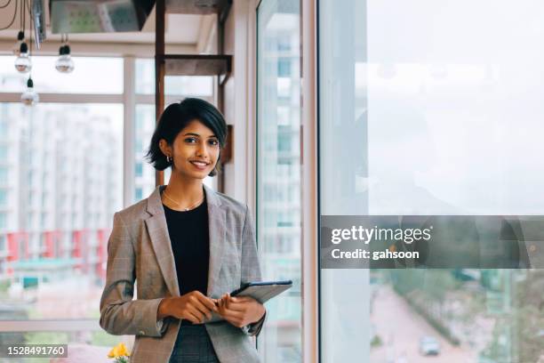 young businesswoman posing by window - young professional stock pictures, royalty-free photos & images