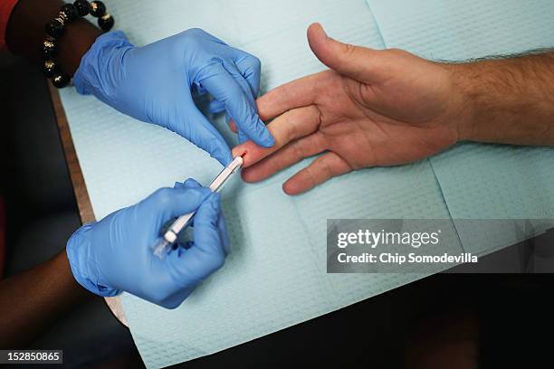 Health educator uses a syringe to take a drop of blood from a man's finger while conducting an HIV test at the Whitman-Walker Health Elizabeth Taylor...