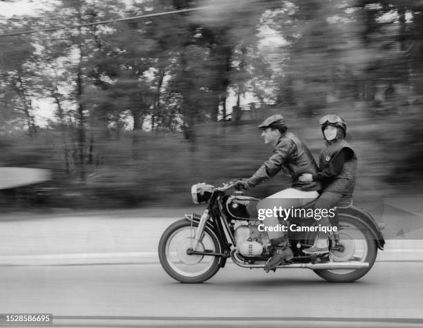 Man and woman flying down the road on a motorcycle with the back ground blurred