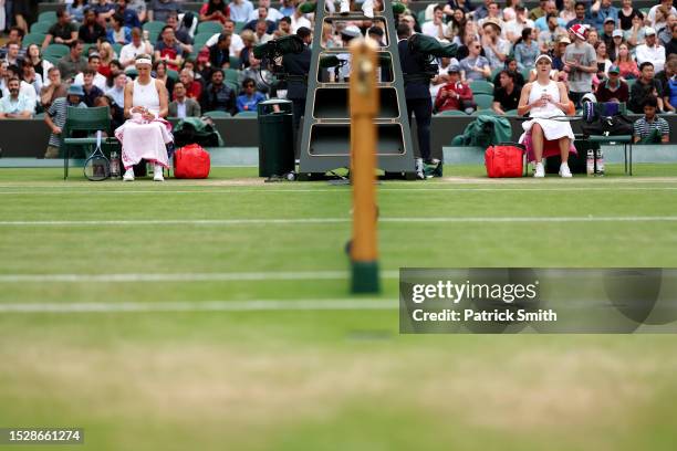 Elina Svitolina of Ukraine and Victoria Azarenka take a break before switching ends in the Women's Singles fourth round match during day seven of The...