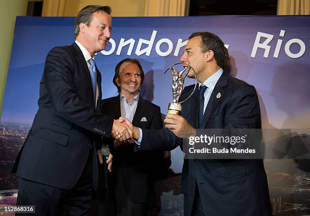 British Prime Minister David Cameron shakes hands with Rio de Janeiro state Governor Sergio Cabral after giving him a trophy during the Laureus...