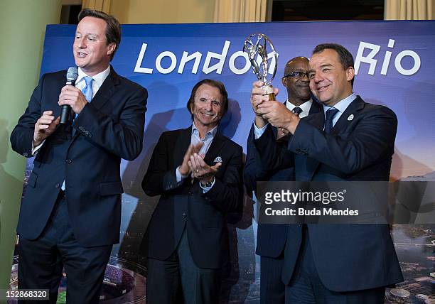 British Prime Minister David Cameron shakes hands with Rio de Janeiro state Governor Sergio Cabral after giving him a trophy during the Laureus...