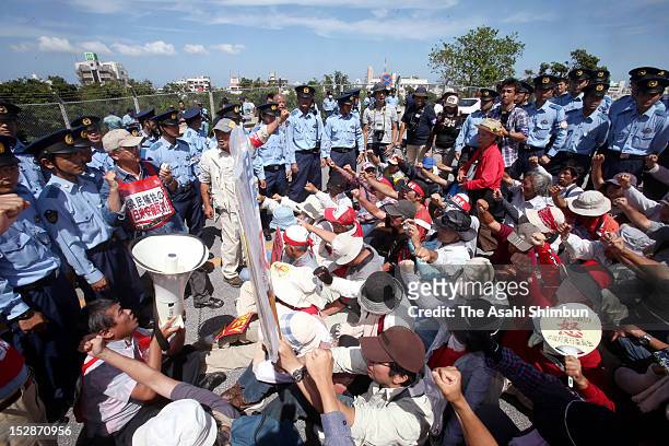 People hold a sit-in protest on the road lead to the Futenma Air Base while police officers surround on September 27, 2012 in Ginowan, Okinawa,...