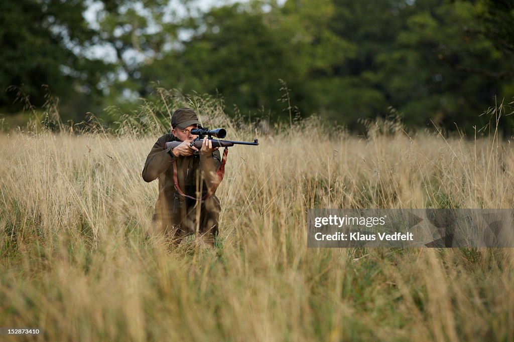 Male hunter aiming with rifle