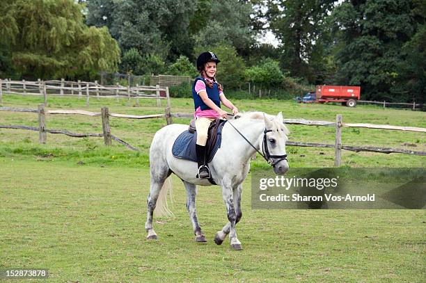 happy girl riding grey pony - zadel stockfoto's en -beelden