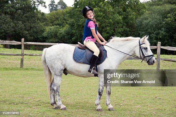 girl with beaming smile riding grey pony - 乗馬帽 ストックフォトと画像