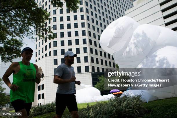 Joggers pass by one of the rabbits of Australian artist Amanda Parer's monumental installation "Intrude". The public art exhibition consists of...