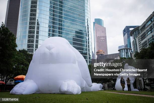People walk by inflatable rabbits which are part of Australian artist Amanda Parer's monumental installation titled "Intrude". The public art exhibit...