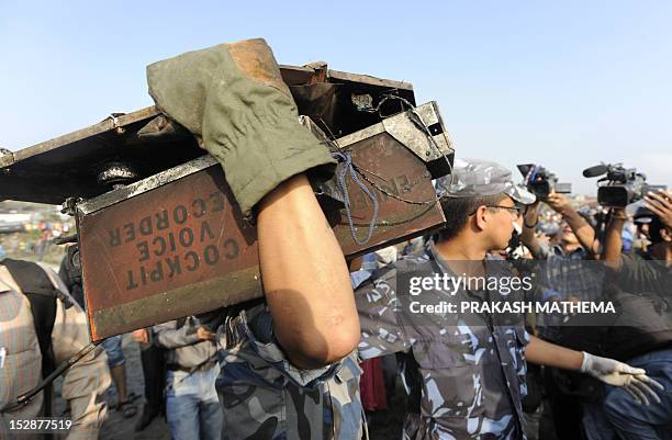 Nepalese police man carries the black box after it was recovered from a Sita airplane wreckage after it crashed in Manohara, Bhaktapur on the...