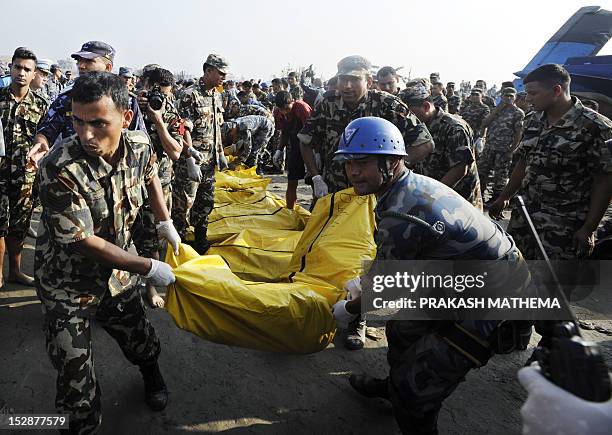 Nepalese rescue team members move bodies found in the wreckage of a Sita airplane after it crashed in Manohara, Bhaktapur on the outskirts of...