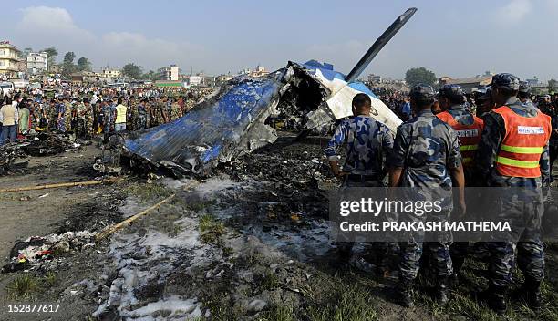 Nepalese rescue team members gather around at the remains of a Sita airplane after it crashed in Manohara, Bhaktapur on the outskirts of Kathmandu on...