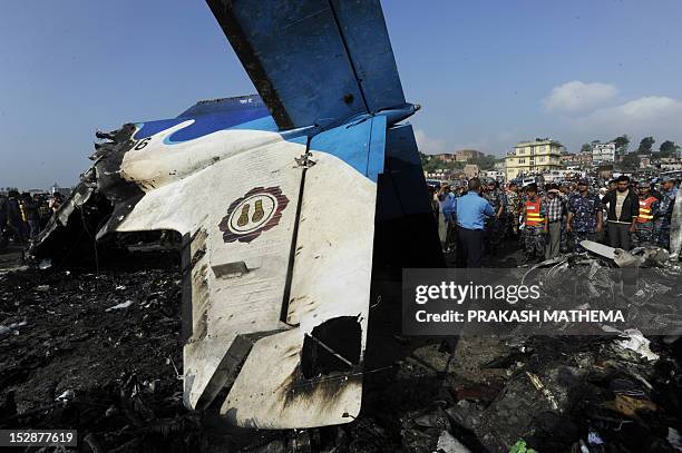 Nepalese rescue team members gather around at the remains of a Sita airplane after it crashed in Manohara, Bhaktapur on the outskirts of Kathmandu on...
