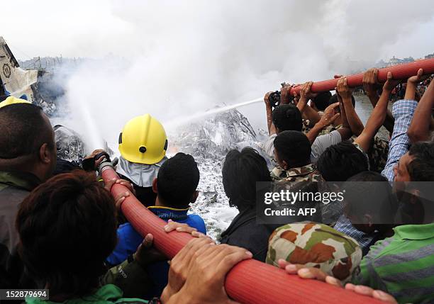 Nepalese fireman and volunteers help extinguish flames from the wreckage of the Sita airplane after it crashed in Manohara, Bhaktapur on the...