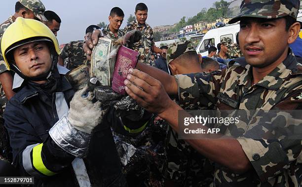 Nepalese fireman and rescue workers show a passport and money collected from the wreckage of a Sita airplane after it crashed in Manohara, Bhaktapur...