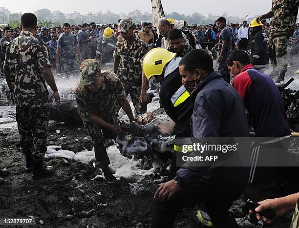 Nepalese fireman and rescue workers remove a body from a Sita airplane after it crashed in Manohara, Bhaktapur on the outskirts of Kathmandu on...