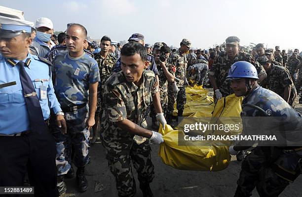 Nepalese rescue team members move bodies found in the wreckage of a Sita airplane after it crashed in Manohara, Bhaktapur on the outskirts of...