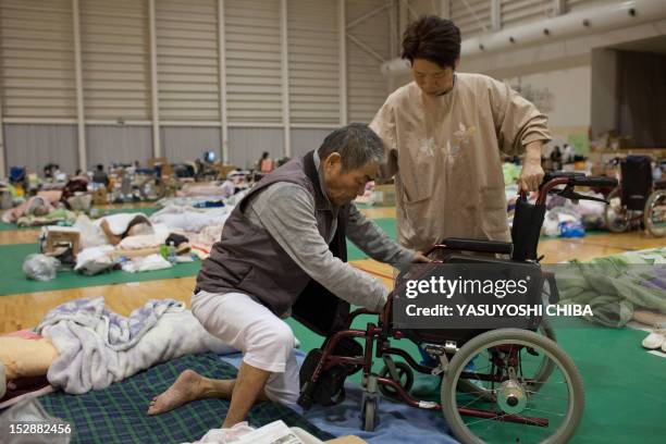 Shizuko Abe helps her paralysed 73-year-old husband Yoshio at an evacuation centre for hospital patients displaced by the earthquake and tsunami, in...