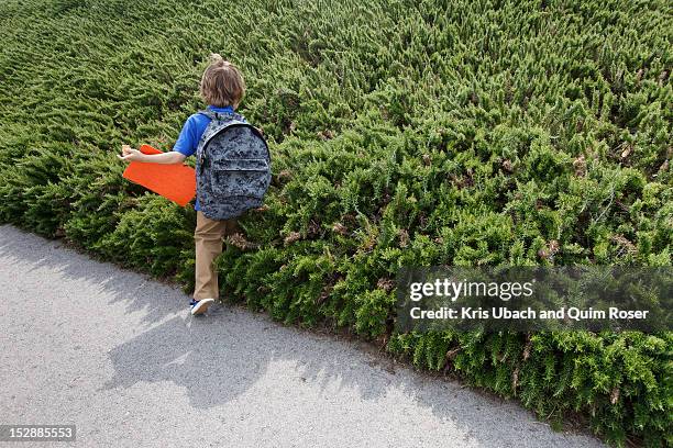 boy walking by shrubs outdoors - entering school stock pictures, royalty-free photos & images