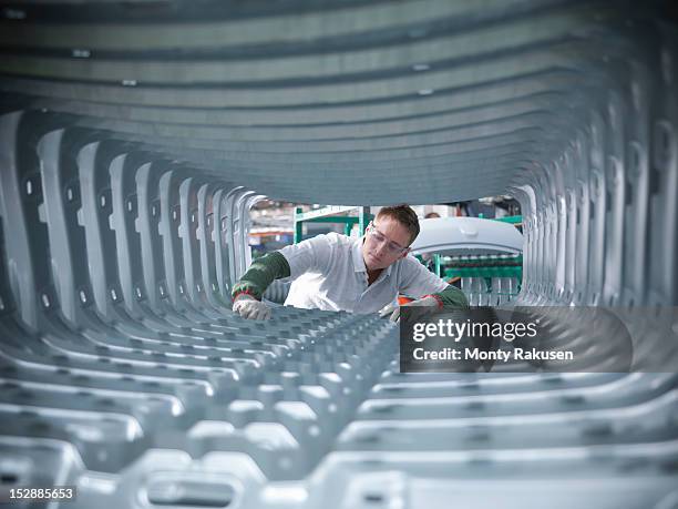 worker inspecting car body pressings in car factory - autofabrik stock-fotos und bilder