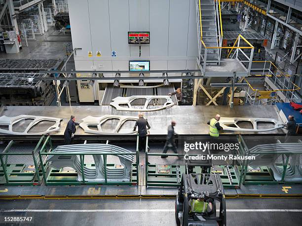 high angle view of workers handling car parts as they come out of press in car factory - manufacturing efficiency stock pictures, royalty-free photos & images