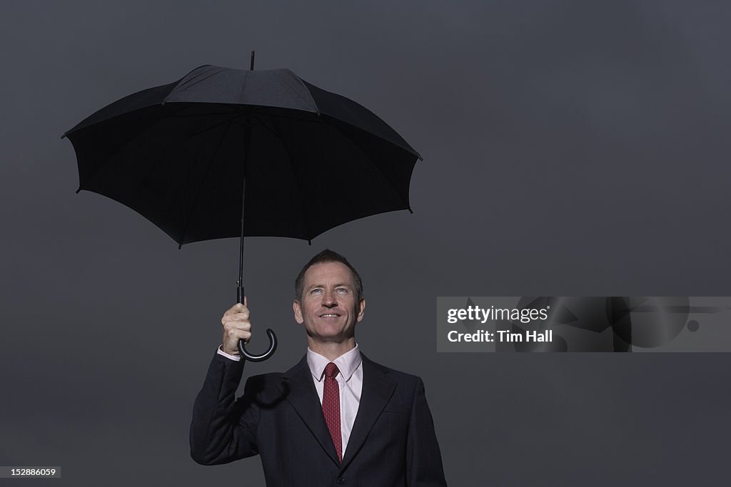 Businessman standing under umbrella