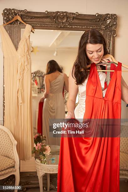 woman examining dress in store - red dress stock pictures, royalty-free photos & images