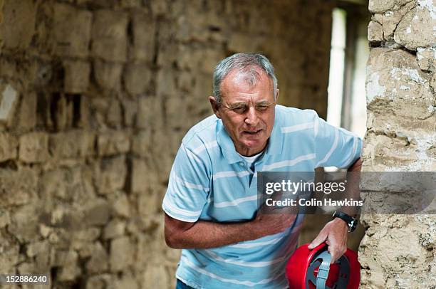 construction worker clutching his chest - heart attack stockfoto's en -beelden