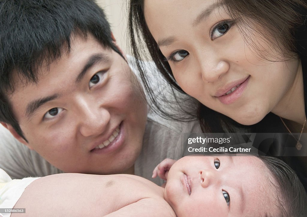 Close up of parents smiling with baby