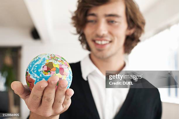 teenage boy holding miniature globe - business man holding stock-fotos und bilder