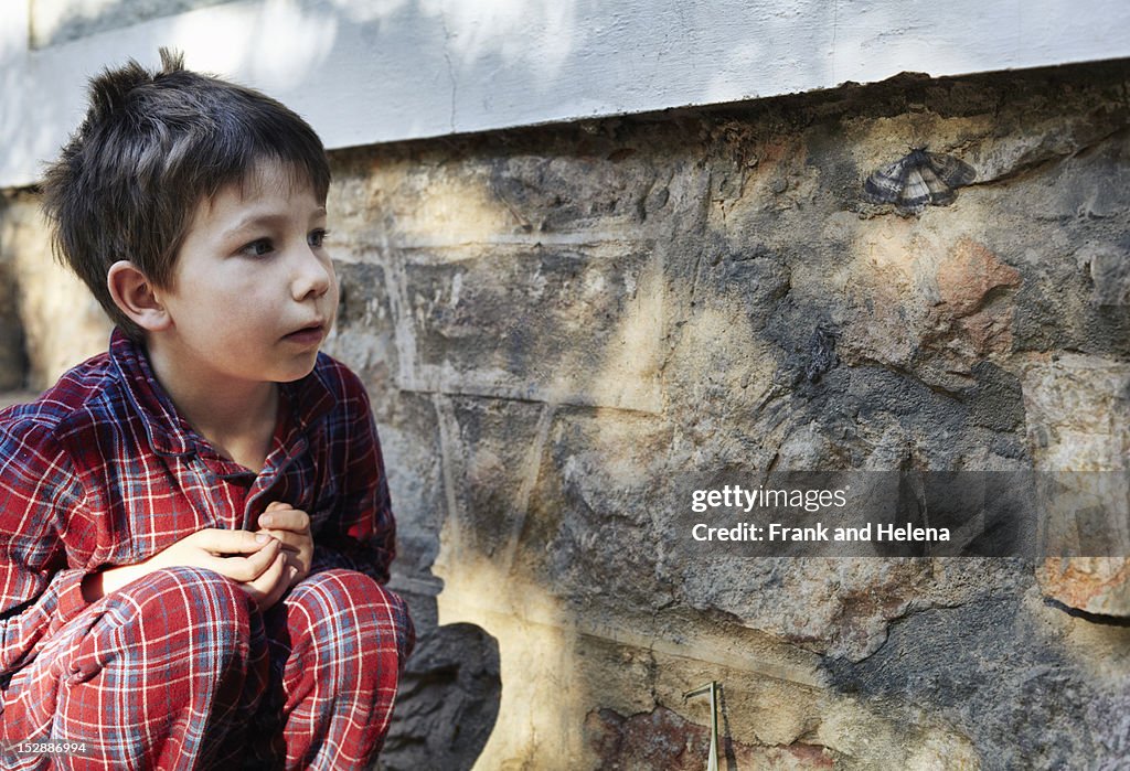 Boy examining moth on stone wall