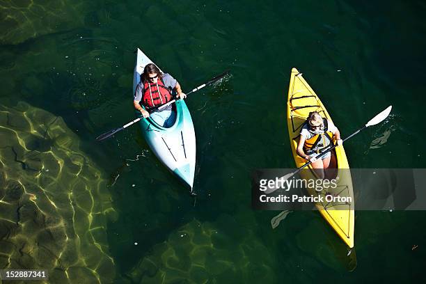 a young adult couple kayaking on a sunny day on a lake in idaho. - sandpoint stock pictures, royalty-free photos & images