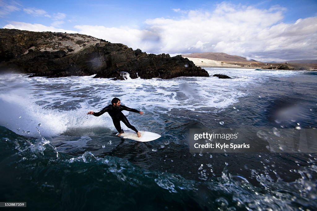 A male surfer bottom turns around a breaking wave while surfing in Northern Baja, Mexico.