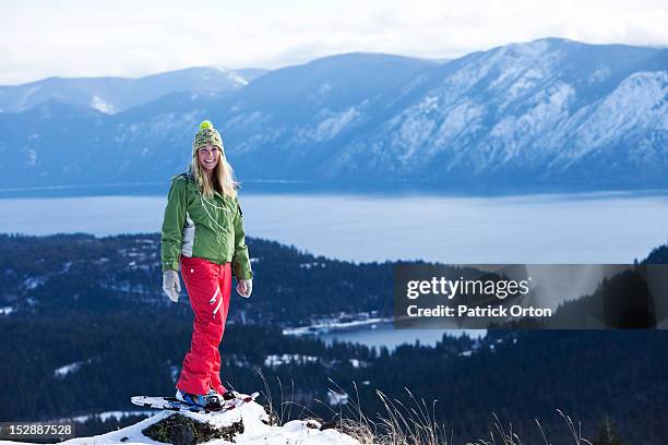 a beautiful young woman smiles while snowshoeing above a lake in idaho. - pend orielle lake stock pictures, royalty-free photos & images