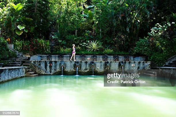 a beautiful woman relaxing next to a hot springs surrounded by a lush jungle and flowers in bali, indonesia. - patrick walker stock pictures, royalty-free photos & images