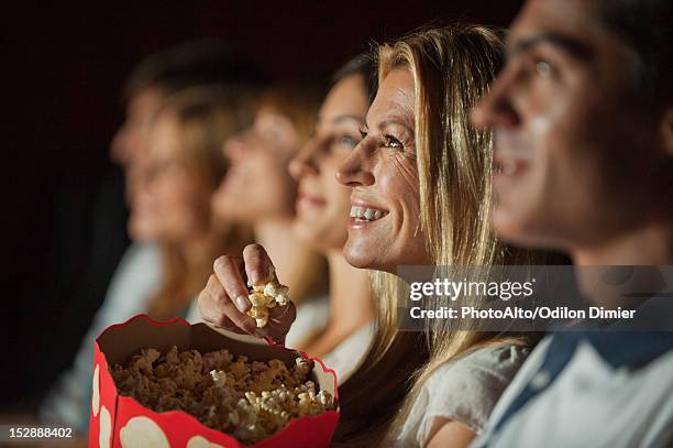 woman eating popcorn while watching movie in theater - film 2012 fotografías e imágenes de stock