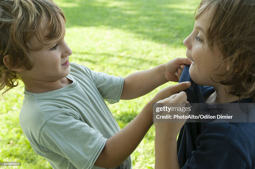 Boys fighting, one gripping the other's shirt