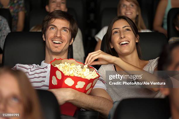 couple eating popcorn in movie theater - medium group of people stock pictures, royalty-free photos & images