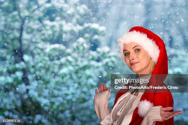 woman wearing santa hat, wintery scene in background, portrait - kerstmuts stockfoto's en -beelden