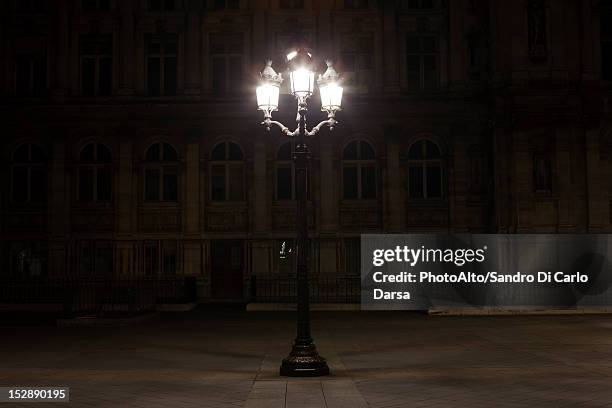 street lamp illuminated at night in place de l'hotel de ville, paris, france - paris france at night stock pictures, royalty-free photos & images