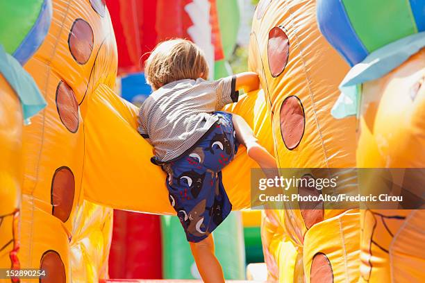 boy playing in bouncy castle, rear view - bouncy castle stock-fotos und bilder