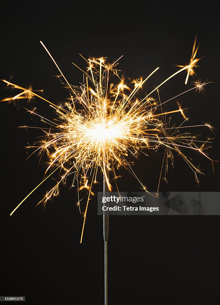 Burning sparkler on black background