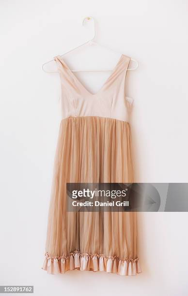 dress with frill on hanger against white wall - beige dress stock pictures, royalty-free photos & images