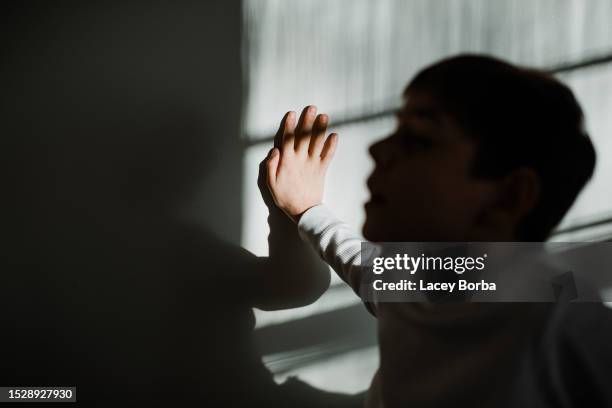 young boy with autism hand in focus face silhouette - autismus stock-fotos und bilder