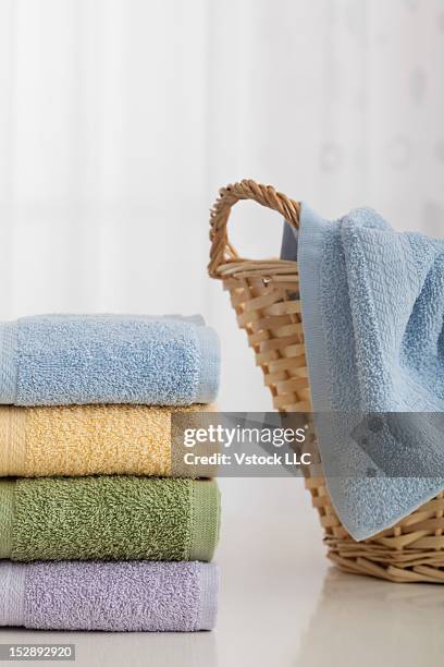 studio shot of stack of pastel colored towels with wicker basket - laundry basket imagens e fotografias de stock