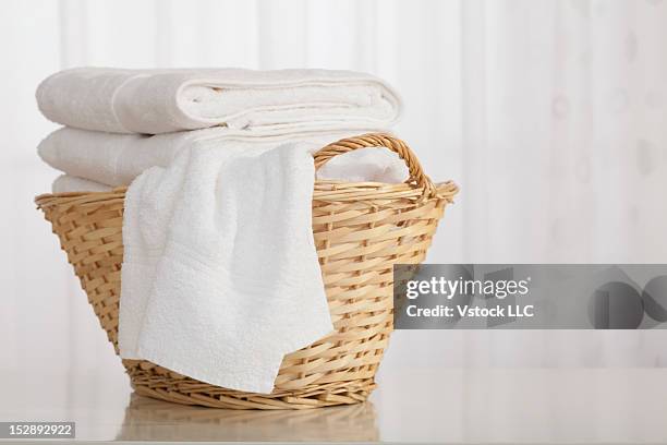 studio shot of stack of white towels in wicker basket - white laundry foto e immagini stock